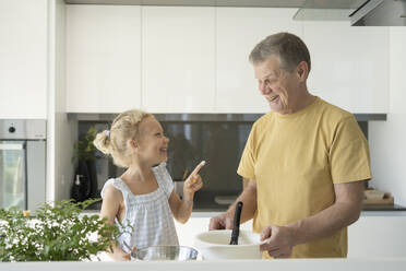 Lächelndes Mädchen, das auf den Großvater in der Küche zeigt - SVKF01320