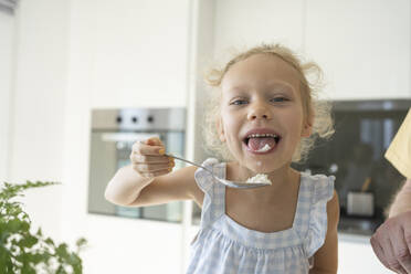 Girl tasting flour in kitchen at home - SVKF01321