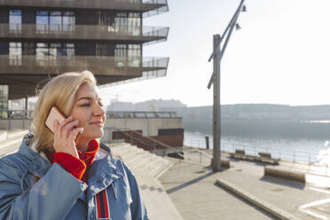 Lächelnde Frau, die mit einem Smartphone telefoniert - IHF01307