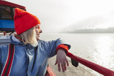 Happy woman leaning on railing on ferry - IHF01317