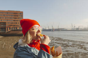 Frau mit Sonnenbrille isst Fisch und Chips - IHF01321