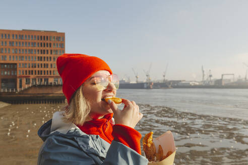 Woman wearing sunglasses eating fish and chips - IHF01321