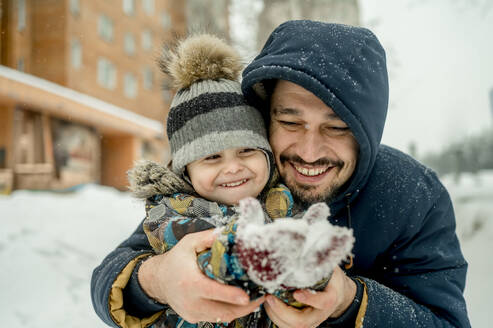Vater und Sohn in warmer Kleidung genießen zusammen im Schnee - ANAF01065