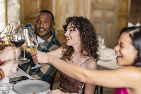 Freunde stoßen mit Weingläsern bei einer Dinnerparty im Restaurant an - JCCMF09577