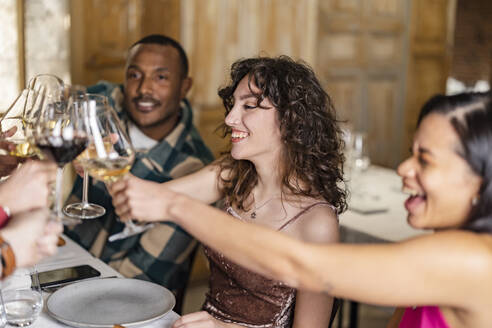 Friends toasting wineglasses at dinner party in restaurant - JCCMF09577