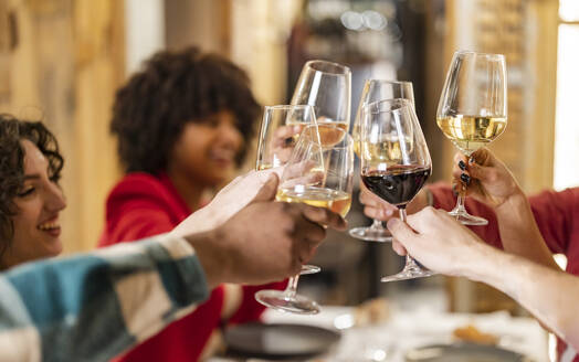 Junge Freunde stoßen in einem Restaurant mit Weingläsern an - JCCMF09589