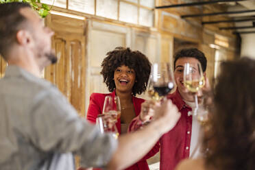 Glückliche Freunde stoßen mit Weingläsern an und feiern im Restaurant - JCCMF09625