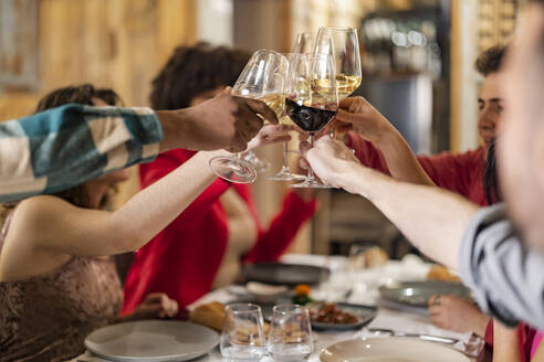 Freunde stoßen mit Weingläsern am Tisch im Restaurant an - JCCMF09635