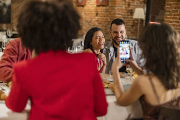 Frau, die ein Bild von Freunden mit ihrem Smartphone aufnimmt - JCCMF09638