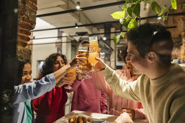 Glückliche Freunde stoßen im Restaurant mit Biergläsern an - JCCMF09644