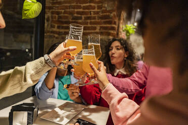 Friends toasting beer glasses at table in restaurant - JCCMF09647