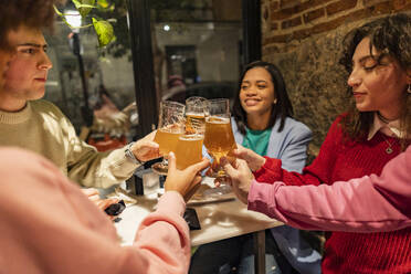 Happy friends toasting beer glasses at restaurant - JCCMF09648