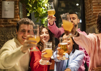 Happy multiracial friends toasting beer glasses at brewery pub Stock Photo  by engy91