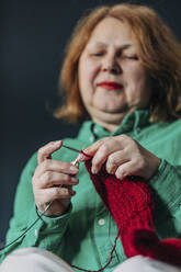 Ältere Frau strickt roten Pullover - VSNF00564