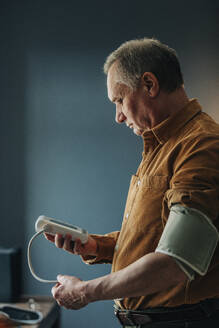 Älterer Mann im Ruhestand prüft Blutdruck an der Wand - VSNF00569