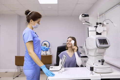 Smiling patient talking to ophthalmologist at medical clinic - SANF00066