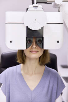 Patientin bei der Augenuntersuchung durch den Phoropter in der Klinik - SANF00070