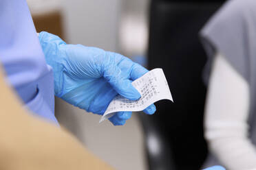 Hand eines Arztes mit Handschuh, der die Messwerte in einer Klinik hält - SANF00071