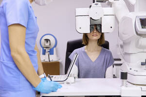 Doctor with patient doing eyesight check up through phoropter at clinic - SANF00073