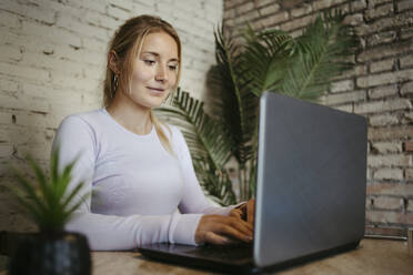 Geschäftsfrau beim Tippen auf einem Laptop im Büro - RCPF01727