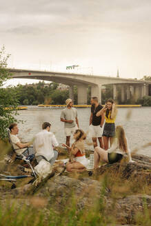 Multirassische männliche und weibliche Freunde genießen zusammen beim Picknick am Meer - MASF35433