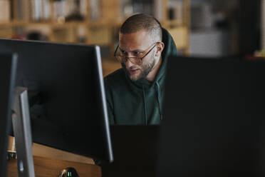 Junger männlicher Programmierer bei der Arbeit am Computer in einem Start-up-Unternehmen - MASF35570