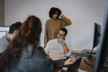 Multirassische weibliche und männliche Computerprogrammierer diskutieren in einem Startup-Unternehmen - MASF35578