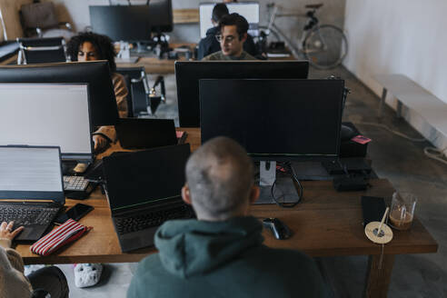 Männliche und weibliche Computerprogrammierer, die in einem Start-up-Unternehmen am Schreibtisch arbeiten - MASF35592