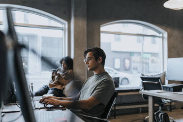 Männlicher Computerprogrammierer mit Laptop bei der Arbeit in einem Start-up-Unternehmen - MASF35607