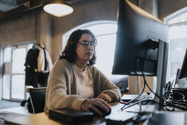 Businesswoman working on computer at desk in startup company - MASF35609