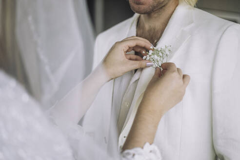 Mittelteil der Braut bei der Anpassung der Boutonniere in der Tasche des Bräutigams bei der Hochzeit - MASF35741