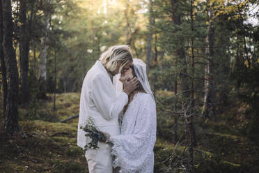 Frisch verheiratetes Paar küsst sich am Hochzeitstag im Wald - MASF35751