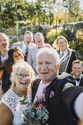 Lächelnde frisch Vermählte halten Erinnerungen mit ihren Lieben in einem fröhlichen Hochzeits-Selfie fest - MASF35786
