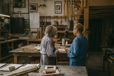 Ältere Handwerkerinnen diskutieren gemeinsam bei der Arbeit in der Reparaturwerkstatt - MASF35821