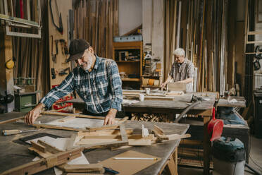 Senior craftsman preparing frame on workbench at repair shop - MASF35840