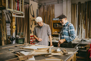 Ältere Handwerker diskutieren gemeinsam bei der Arbeit in der Reparaturwerkstatt - MASF35846