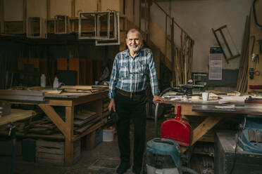 Senior craftsman standing near workbench at carpentry workshop - MASF35855