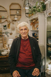 Porträt eines älteren männlichen Besitzers, der in einem Geschäft für Wohnkultur sitzt - MASF35892