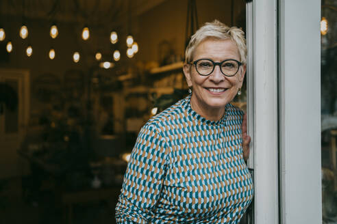 Portrait of senior female owner standing at entrance of store - MASF35895