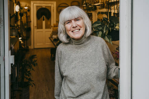 Portrait of smiling senior female owner with gray hair at store doorway - MASF35898