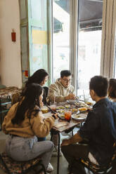 Männliche und weibliche Freunde beim gemeinsamen Mittagessen im Restaurant - MASF35918