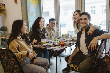 Happy male and female friends enjoying together during lunch at restaurant - MASF35925