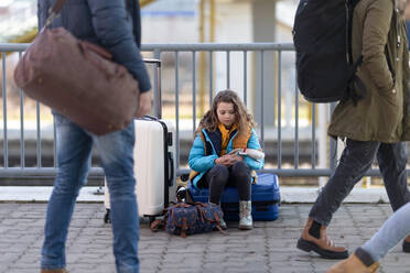 Ein trauriges ukrainisches Einwandererkind mit Gepäck wartet am Bahnhof, ukrainisches Kriegskonzept. - HPIF07040