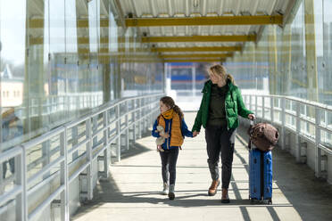 Eine ukrainische Einwanderer-Mutter mit Kind mit Gepäck zu Fuß am Bahnhof, ukrainischen Krieg Konzept. - HPIF07044