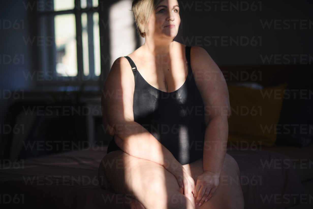 A happy lonely fat woman in underwear relaxing at home. stock photo