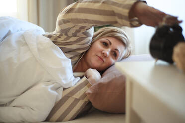 Eine übergewichtige Frau wacht im Bett auf und schaltet den Wecker zu Hause aus. - HPIF07076