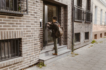 Man standing on steps while locking door of apartment - MASF35985