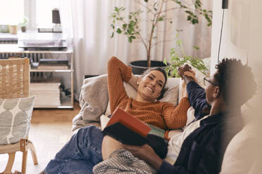Glückliches Paar verbringt seine Freizeit auf dem Sofa zu Hause - MASF36011