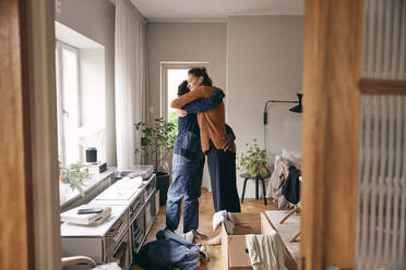 Seitenansicht eines Paares, das sich umarmt, während es zu Hause steht - MASF36018