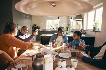 Multigenerational family enjoying together while having food on dining table at home - MASF36037